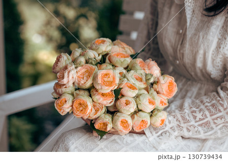 Bouquet in female hands. Bunch of Living Coral roses. 130739434