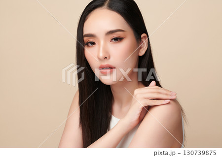A beautiful young Asian woman with clean, fresh skin against a beige background. Skincare, facial treatment, cosmetology, beauty, and spa. An elegant portrait of an Asian woman. 130739875