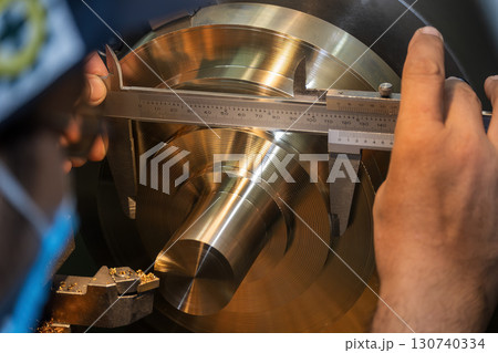 Close up scene the machine operator measuring dimension of metal shaft parts by Vernier caliper. 130740334