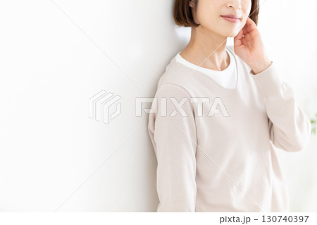 窓際の白壁にもたれるカジュアルのミドル女性 窓際の白壁にもたれるカジュアルのミドル女性 130740397