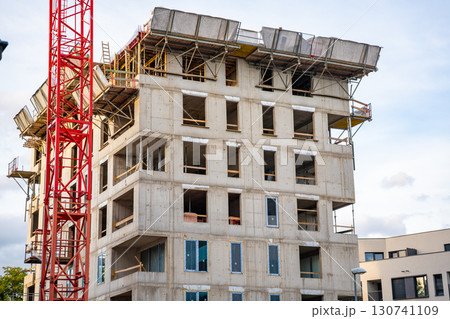 Construction site with cranes and concrete structures during active building process. Concept of modern urban development, housing expansion and civil engineering. Construction site with cranes and concrete structures during active building process. Concept of modern urban development, housing expansion and civil engineering. 130741109