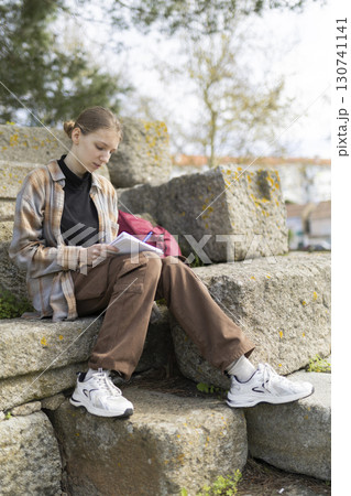 Student writing notes outdoors in archaeological site 130741141