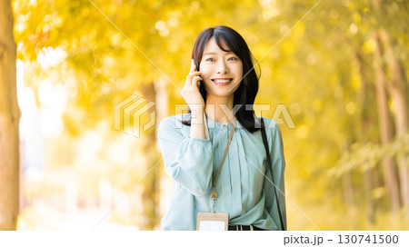 紅葉の街路樹の中、スマートフォンで話す女性 紅葉の街路樹の中、スマートフォンで話す女性 130741500