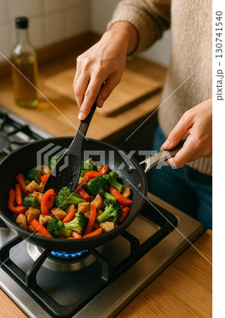 フライパンで炒め物をする手元/家庭料理・健康食・食材調理 130741540