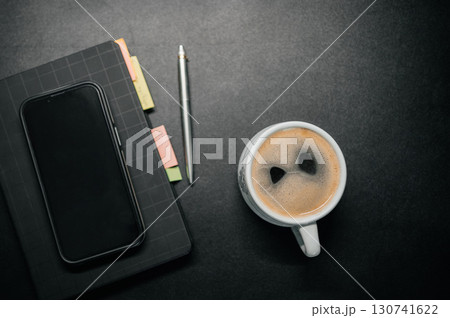 Cup of coffee on desk with notebook, smartphone and pen. Workspace concept, productivity and planning background. Cup of coffee on desk with notebook, smartphone and pen. Workspace concept, productivity and planning background. 130741622