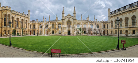 The University of Cambridge panoramic view of a historic college courtyard, featuring a grand, symmetrical facade with Gothic inspired architecture and a central clock tower 130741954