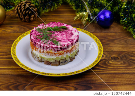 Traditional russian salad "Herring under a fur coat" (shuba) and Christmas decorations on wooden table 130742444