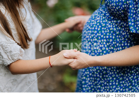 Pregnant mother holding hands with daughter, showing connection and anticipation Pregnant mother holding hands with daughter, showing connection and anticipation 130742505