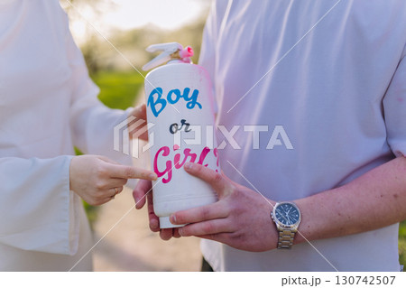 Couple revealing baby gender with color spray during gender reveal celebration outdoors 130742507