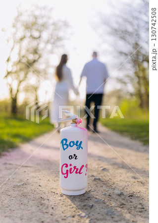 Gender reveal concept with a spray can and couple walking hand in hand in soft sunlight 130742508
