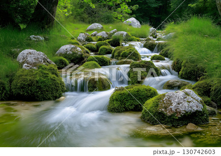 Water gently cascades over moss covered rocks in a serene nature scene, with lush green moss contrasting beautifully with flowing water, creating a peaceful atmosphere. Perfect for nature lovers Water gently cascades over moss covered rocks in a serene nature scene, with lush green moss contrasting beautifully with flowing water, creating a peaceful atmosphere. Perfect for nature lovers 130742603