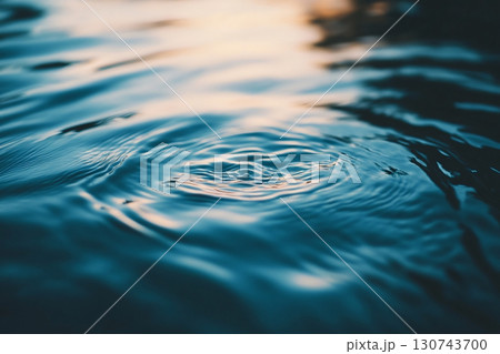 Rippling water reflecting a beautiful sunset with concentric circles spreading out from the center 130743700