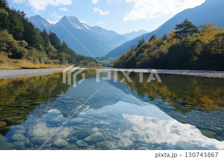 Stunning view of a crystal clear river reflecting the surrounding mountains and autumn foliage 130743867