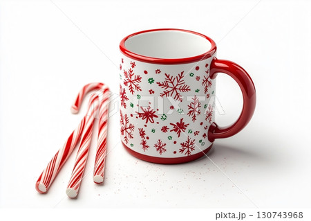 Christmas themed mug with snowflake pattern standing next to candy canes on white background 130743968