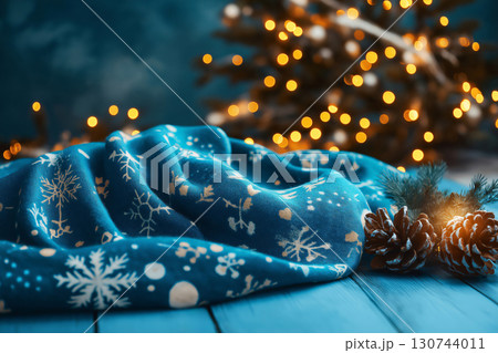 Blue Christmas throw blanket mockup laying on a blue wooden table with pine cones and blurred Christmas lights in the background 130744011