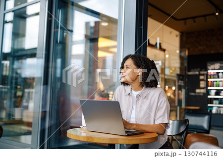 A Young Woman is Engaged in Working on Her Laptop in a Stylish Modern Coffee Shop A Young Woman is Engaged in Working on Her Laptop in a Stylish Modern Coffee Shop 130744116