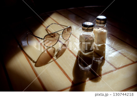 Glasses, pepper shaker and salt shaker on the table in backlight Glasses, pepper shaker and salt shaker on the table in backlight 130744218