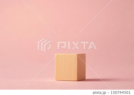 Simple wooden block placed on a soft pink surface with natural lighting Simple wooden block placed on a soft pink surface with natural lighting 130744501
