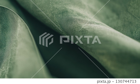 Detailed close-up of textured green fabric with soft draping 130744713