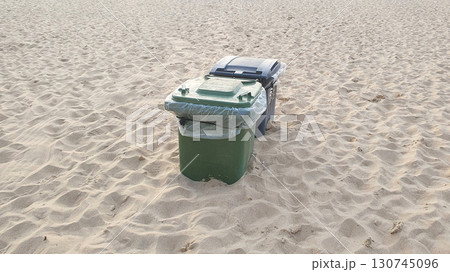 Green and black plastic waste containers buried in yellow sand on the beach. Ostend, Belgien. Green and black plastic waste containers buried in yellow sand on the beach. Ostend, Belgien. 130745096
