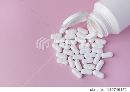 White pills and drugs in plastic bottle on the pink background. Healthcare concept. Space for text. White pills and drugs in plastic bottle on the pink background. Healthcare concept. Space for text. 130746172