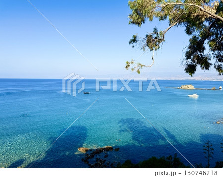 Public beach, summer, beautiful sunny weather. Picturesque beach, waves crashing on the sandy shore. Sea waves beat against the rocks. Cyprus Island, umbrellas, tourist boats, Mediterranean Sea. 130746218
