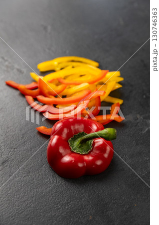 Sliced red and yellow bell peppers with whole pepper on black background, healthy food concept Sliced red and yellow bell peppers with whole pepper on black background, healthy food concept 130746363