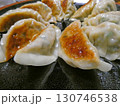 秋の家庭料理！焦げ目が美味しそうな手作りギョウザを黒い皿に盛り付けた写真 130746538