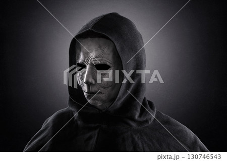 Portrait of a scary man in hooded cloak at night over dark misty background  130746543
