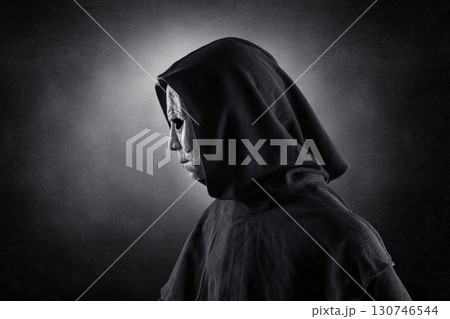 Portrait of a scary man in hooded cloak at night over dark misty background  130746544