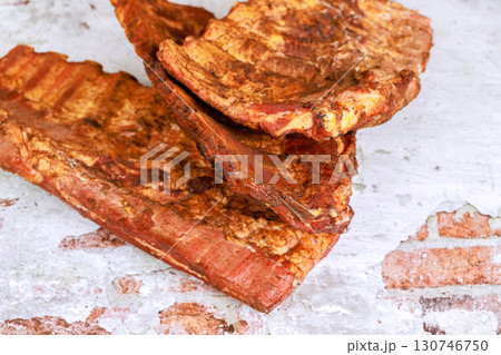 Grilled smoked pork ribs on rustic table, seasoned from backyard barbecue gathering. Grilled smoked pork ribs on rustic table, seasoned from backyard barbecue gathering. 130746750