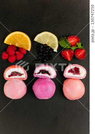 Colorful mochi ice cream with fruity filling on slate board with fresh berries and citrus 130747250