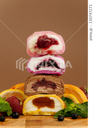 Colorful mochi ice cream with fruity fillings stacked with citrus and berries on wooden board 130747271
