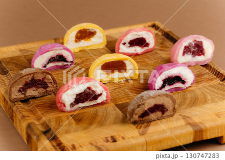 Assorted colorful mochi ice cream halves on wooden board, close-up view, studio lighting 130747283