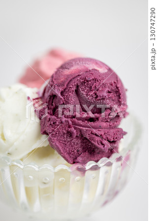 Close-up of colorful ice cream scoops in glass bowl on white background 130747290