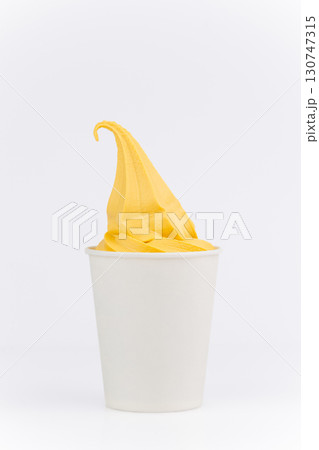 Yellow mango ice cream swirl in white paper cup on clean white background, close up 130747315
