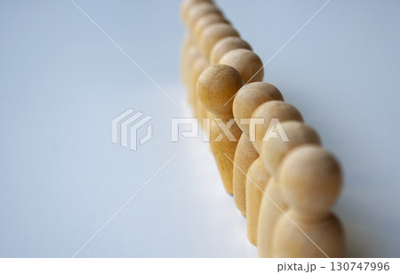 A series of beige wooden dolls aligned in a line with one of them stood out among them highlighting individuality or difference. A series of beige wooden dolls aligned in a line with one of them stood out among them highlighting individuality or difference. 130747996