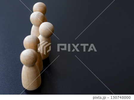 Wooden dolls aligned vertically on a white surface illustrating simplicity and uniformity with one stood up representing courage. Wooden dolls aligned vertically on a white surface illustrating simplicity and uniformity with one stood up representing courage. 130748000