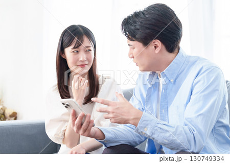 困った表情でスマートフォンを見る男女 130749334