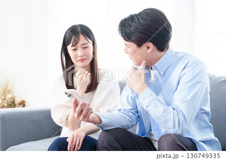 困った表情でスマートフォンを見る男女 困った表情でスマートフォンを見る男女 130749335