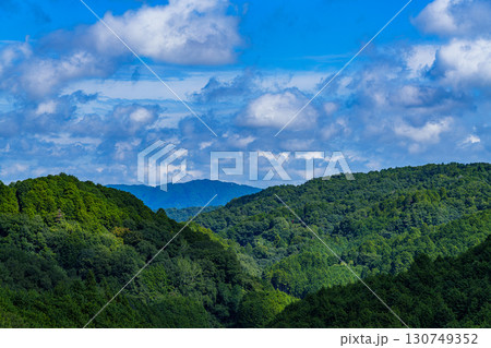 澄み渡る青空に浮かぶ綿雲と山並みの向こうに見える笠置の山 130749352