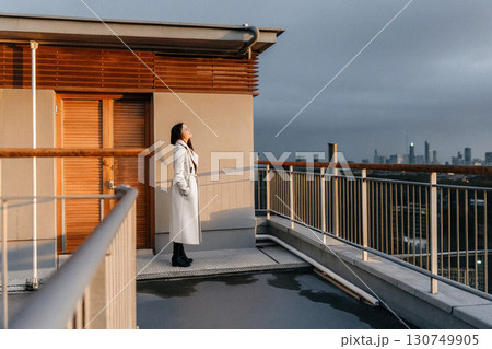 A woman standing alone on a rooftop at dusk. A woman standing alone on a rooftop at dusk. 130749905