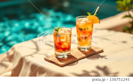Summer pool party scene with two Pimm's Cup cocktails resting on a table next to a shimmering swimming pool Summer pool party scene with two Pimm's Cup cocktails resting on a table next to a shimmering swimming pool 130751245