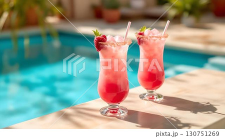 Pink drinks with straws on a table near a pool, capturing the essence of a vibrant summer party 130751269