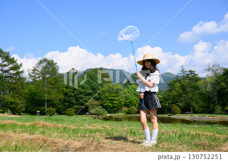 青空の下で虫取りを楽しむ女の子 130752251