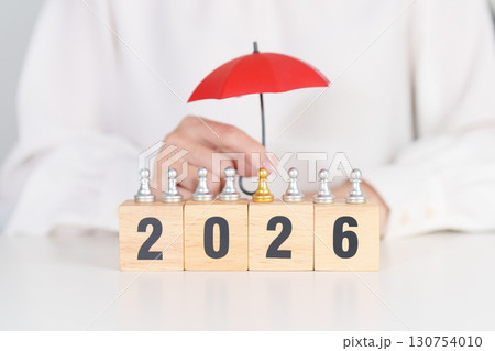 Happy New Year 2026 with hand holding red umbrella cover people chess. life Insurance, health medical, leadership, protection, safety and New year holiday Concepts 130754010