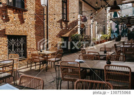 Outdoor dining area with string lights and rustic architecture in a cozy courtyard on a sunny day Outdoor dining area with string lights and rustic architecture in a cozy courtyard on a sunny day 130755068