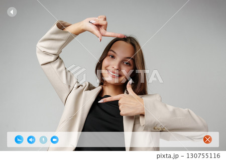 Woman gesturing with fingers in creative framing pose in studio setting during daytime 130755116
