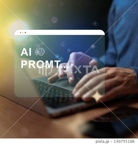 Creative professional working on AI prompt generation at night with a laptop and warm light in the background 130755186