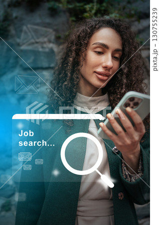 Woman engaged in job search using smartphone while wearing a stylish coat in a modern urban setting 130755239